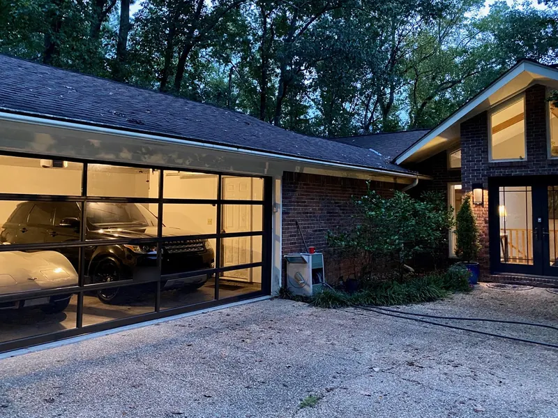 The same garage at dusk with a new full-view glass and black aluminum door